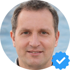 ortrait of a middle-aged man with short, graying hair, smiling with a backdrop of a serene ocean. Verified profile badge is visible in the corner.