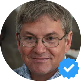  John T. smiling, wearing glasses and a checkered shirt, symbolizing a satisfied client of Hellamaid cleaning service.