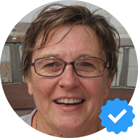 ortrait of Mary L, a satisfied customer of Hellamaid cleaning service, smiling in a bright kitchen.