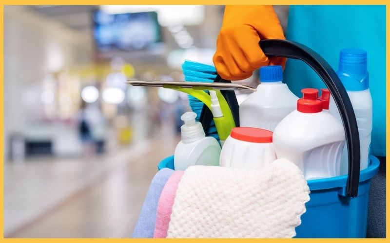 A professional cleaner holding a bucket of cleaning supplies.