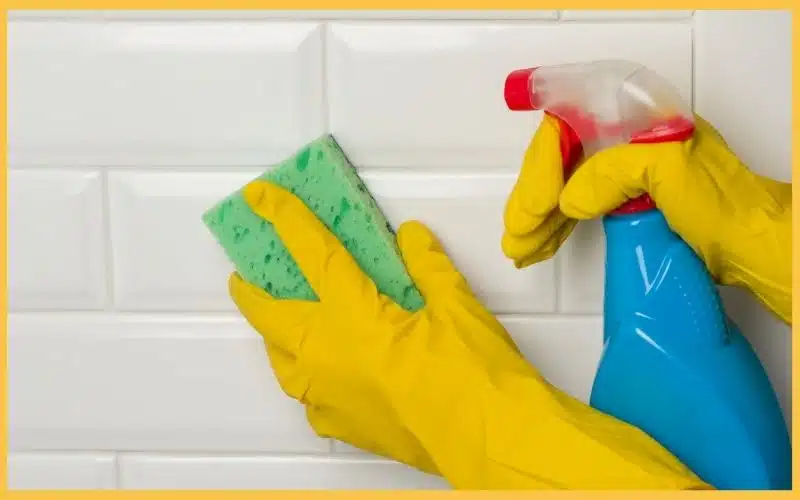 A yellow cleaning gloves with a spray and sponge to clean.