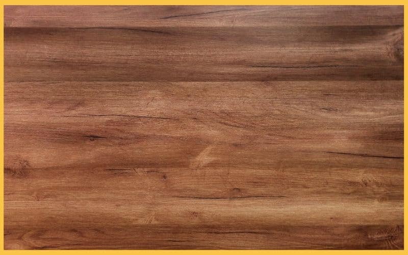 Close-up of a wooden surface with a natural grain pattern, framed by a yellow border. Textured and warm-toned, suggesting a rustic vibe.