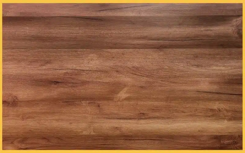 Close-up of a wooden surface with a natural grain pattern, framed by a yellow border. Textured and warm-toned, suggesting a rustic vibe.