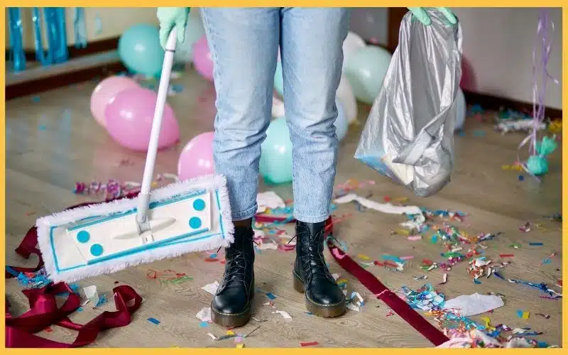 A cleaner with a sweeper and trash bag, symbolizing readiness to clean the post-party mess.