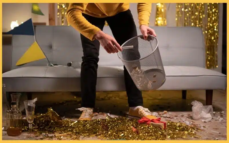 A person in yellow picking up part poppers on the floor.