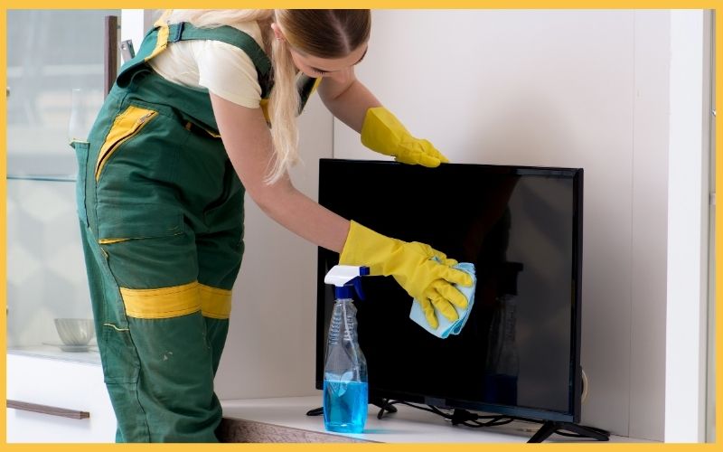 A professional cleaner wiping a TV.