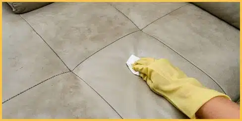A professional cleaning service in Canada wiping a leather couch.