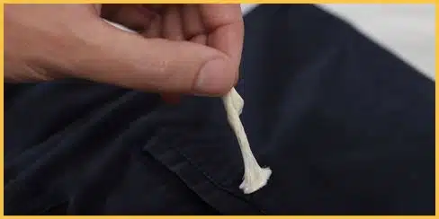 Hand removing chewing gum from couch fabric.