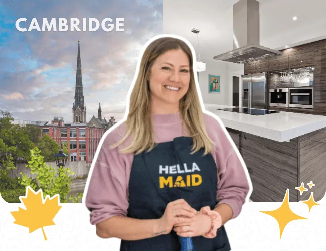 Hellamaid team member posing with a cleaning tool in a high-end kitchen, featuring the Cambridge city skyline