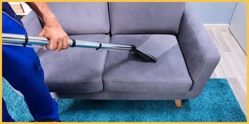An expert cleaner vacuuming a sofa.