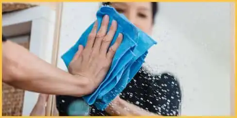 A cleaner using a microfiber cloth to clean a mirror.