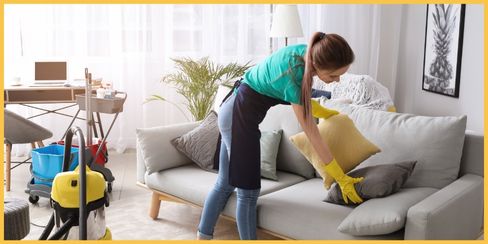 A professional cleaning lady in Calgary fixing pillows of a couch.