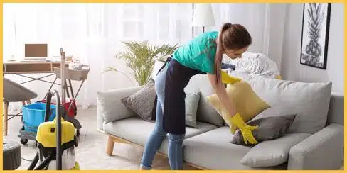 A professional cleaning lady in Calgary fixing pillows of a couch.