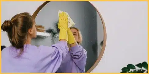 A person wiping the mirror to clean.
