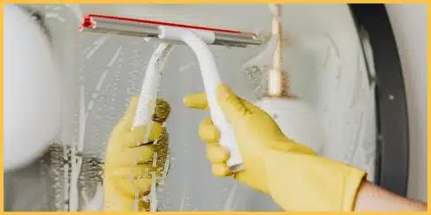 Gloved hand that's cleaning a mirror.