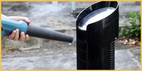 A person vacuuming a fan to clean.