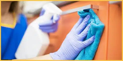 Gloved hands that's cleaning a cabinet.