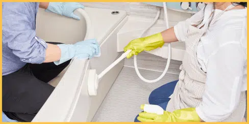 Two cleaners that are cleaning the bathtub.