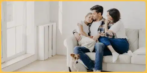 Family of three with their dog in a clean living room.