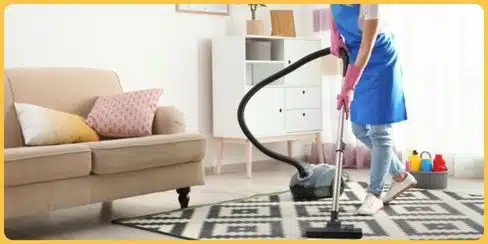 Cleaner that's vacuuming a living area's carpet.