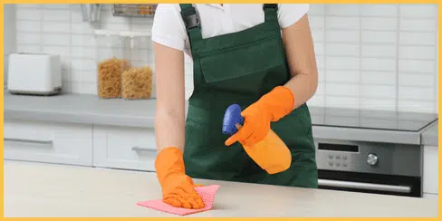 Cleaner wiping the kitchen countertop.